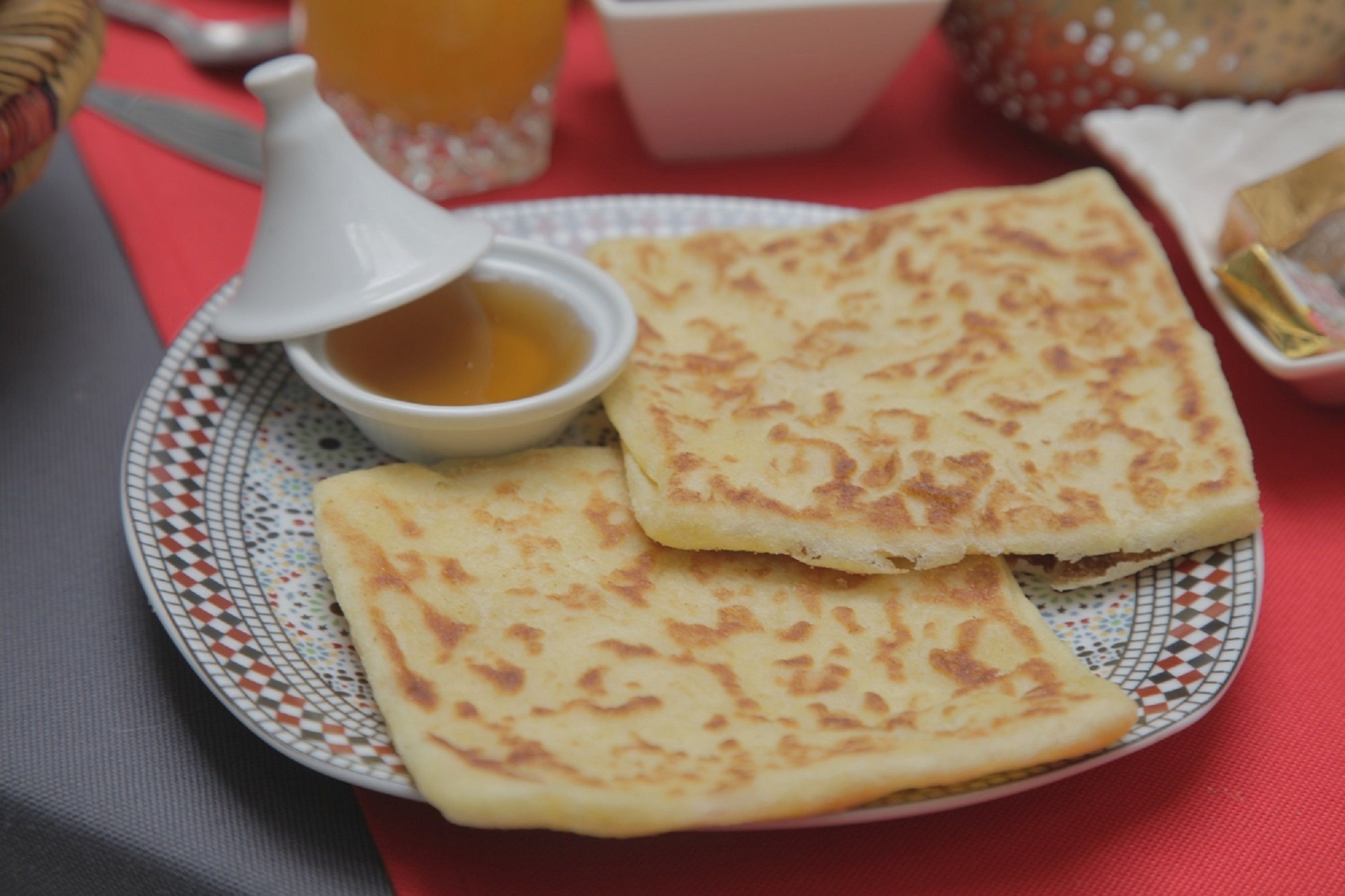 A plate with two pieces of flatbread and a small bowl of sauce.