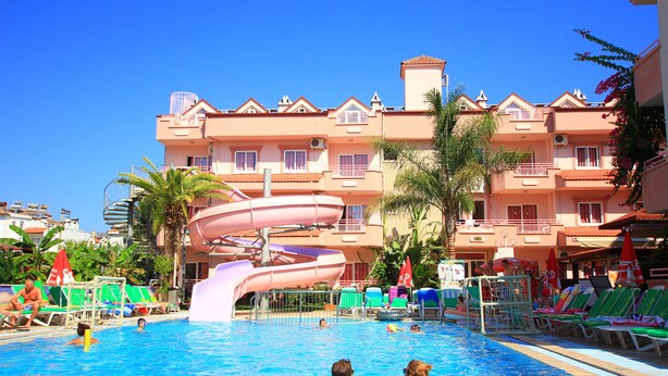 Une piscine avec un toboggan, des chaises longues et un bâtiment doté de balcons en arrière-plan.