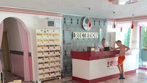 Un espace d’accueil doté d’un sol en marbre, d’un comptoir de réception, d’une horloge murale et d’un mur sur lequel est affiché un panneau indiquant « RÉCEPTION ».