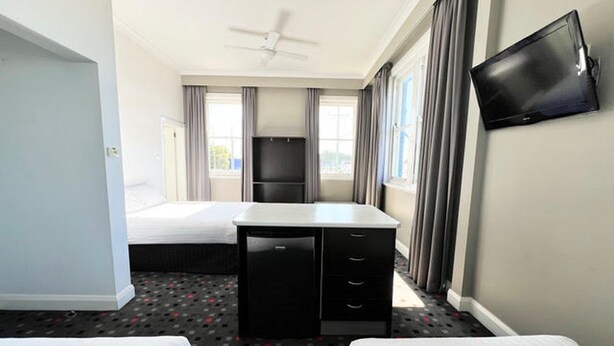 A hotel room with two beds, a desk, a television, and a ceiling fan. - The Sunnyside Tavern, Broadmeadow (Broadmeadow)