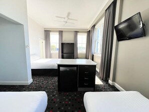 A hotel room with two beds, a desk, a television, and a ceiling fan. - The Sunnyside Tavern, Broadmeadow (Broadmeadow)