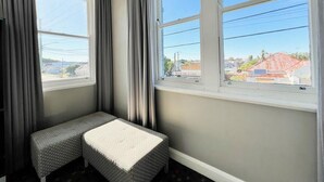 A corner room with two windows, a bench, and a view of buildings outside. - The Sunnyside Tavern, Broadmeadow (Broadmeadow)