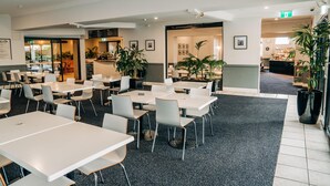 A spacious indoor dining area with multiple tables and chairs, a coffee bar, and potted plants. - The Sunnyside Tavern, Broadmeadow (Broadmeadow)