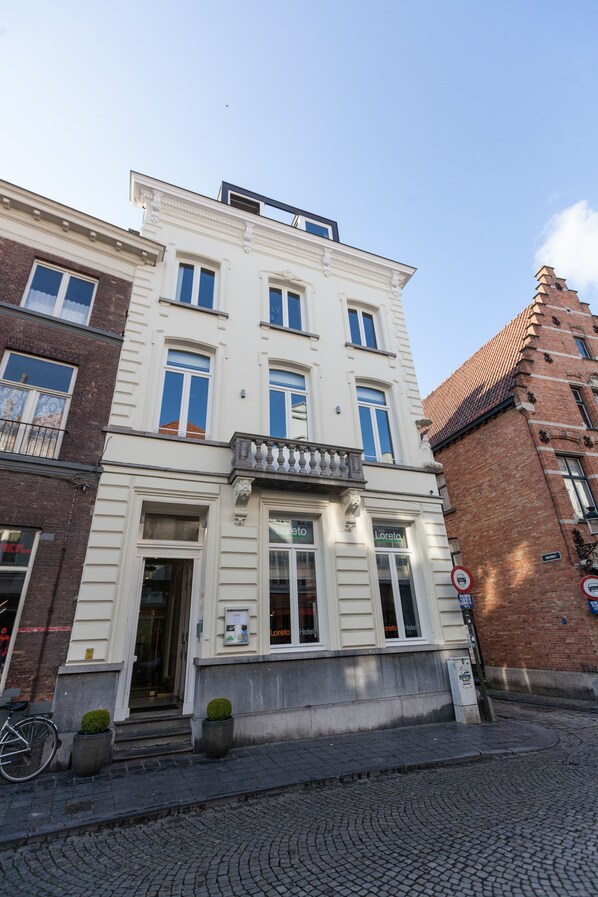 A multi-story building with a white facade, large windows, and a balcony. - Hotel Loreto (Bruges)
