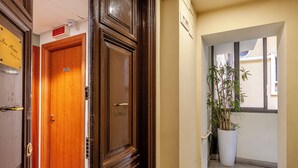 Passadís amb una porta de fusta, una planta en test i un senyal que indica el tipus d'habitació.