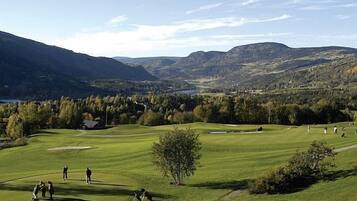 Un campo de golf con una vista panorámica de montañas y un lago.