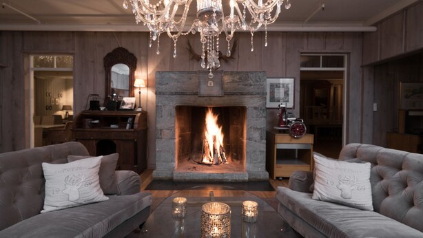 A cozy living room with a fireplace, two sofas, a chandelier, and a coffee table with candles. - Nermo Hotell (Øyer)