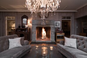 A cozy living room with a fireplace, two sofas, a chandelier, and a coffee table with candles.