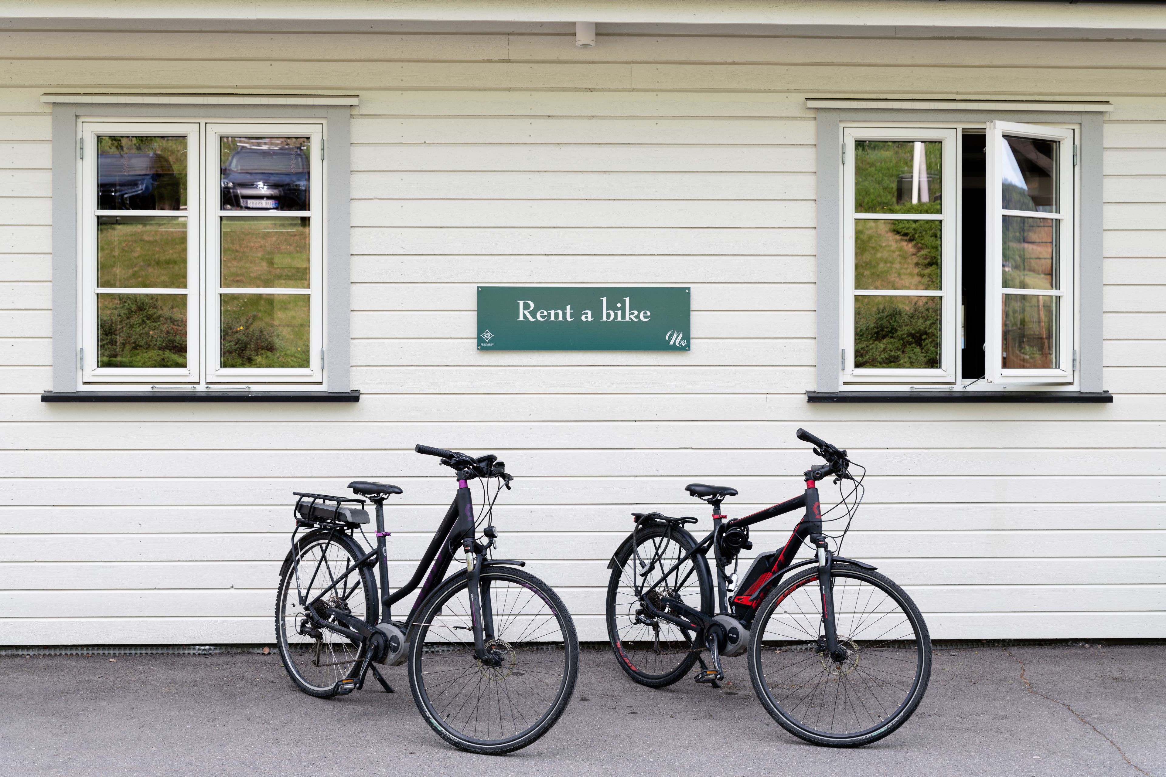 Un edificio con un cartel que dice 'Rent a bike' y dos bicicletas estacionadas adelante.