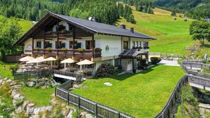 A two-story hotel with outdoor seating and a mountain view. - Ski- & Wanderhotel Berghof (Bad Kleinkirchheim)