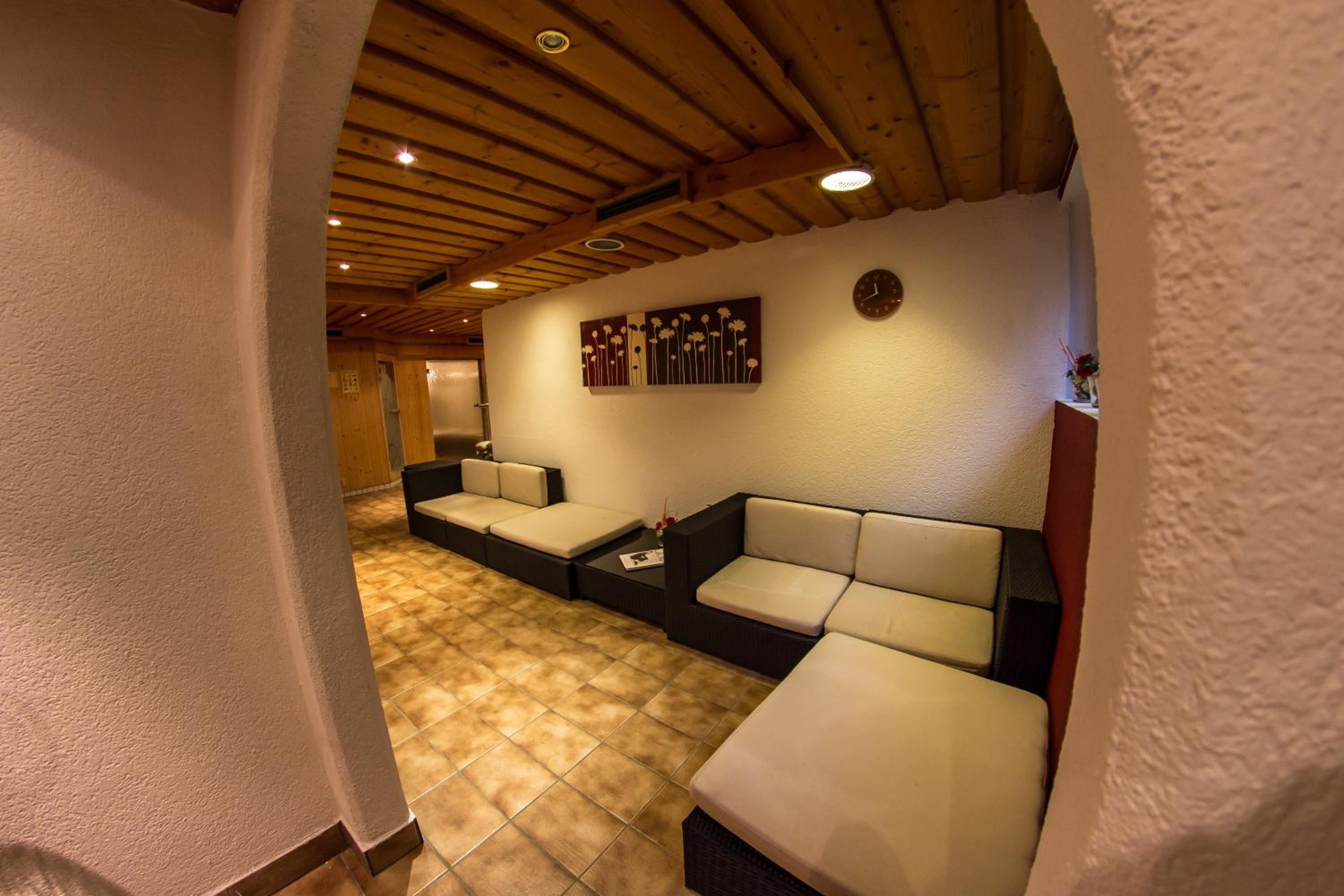 Un pasillo con techo de madera, un reloj en la pared y un sofá con cojines.