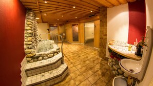 A bathroom with a stone wall, a wooden ceiling, and a sink with a mirror. - Ski- & Wanderhotel Berghof (Bad Kleinkirchheim)