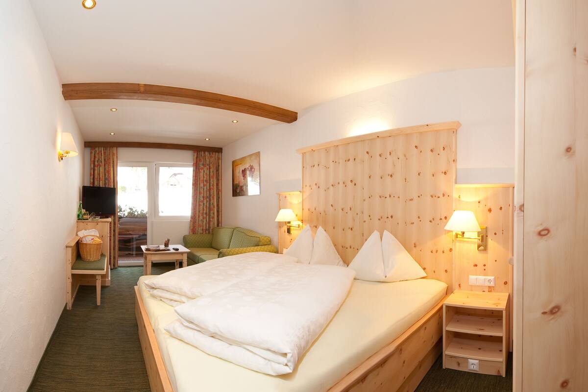Une chambre d’hôtel avec un grand lit, un bureau avec une télévision, une chaise et une petite table.