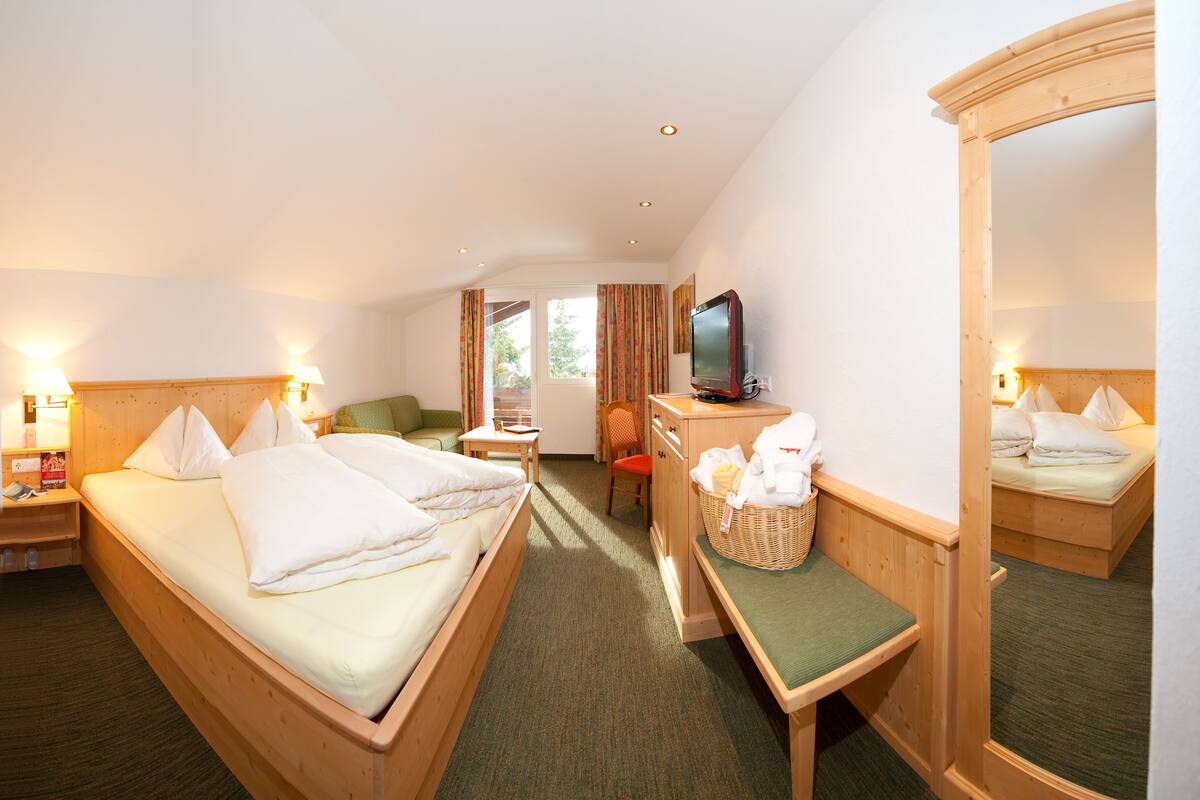 Une chambre d’hôtel avec deux lits, un bureau, une télévision et un miroir.