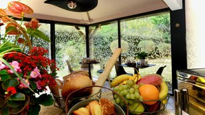 A kitchen with a fruit bowl, bread, and flowers.