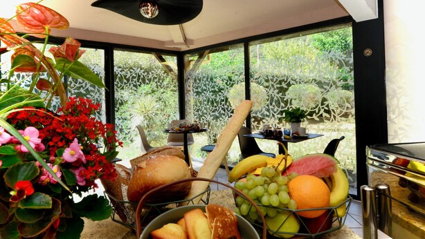 Une cuisine avec un panier de fruits, du pain et des fleurs.
