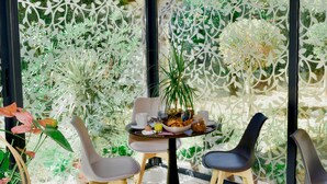 Un coin repas avec une table dressée pour deux personnes, entourée de chaises, et un arrangement floral décoratif en guise de centre de table.