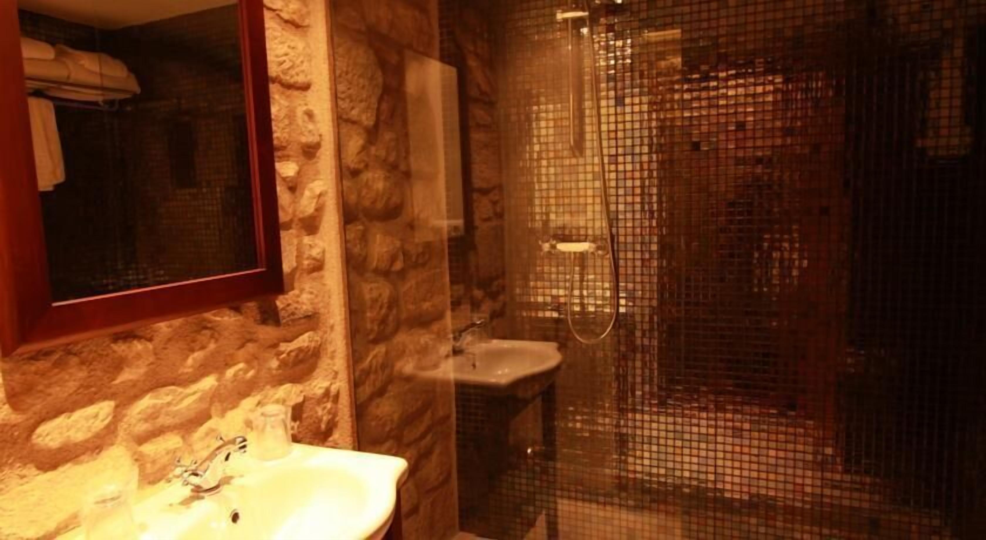 Ein Badezimmer mit Steinwand, Waschbecken und Duschkabine.