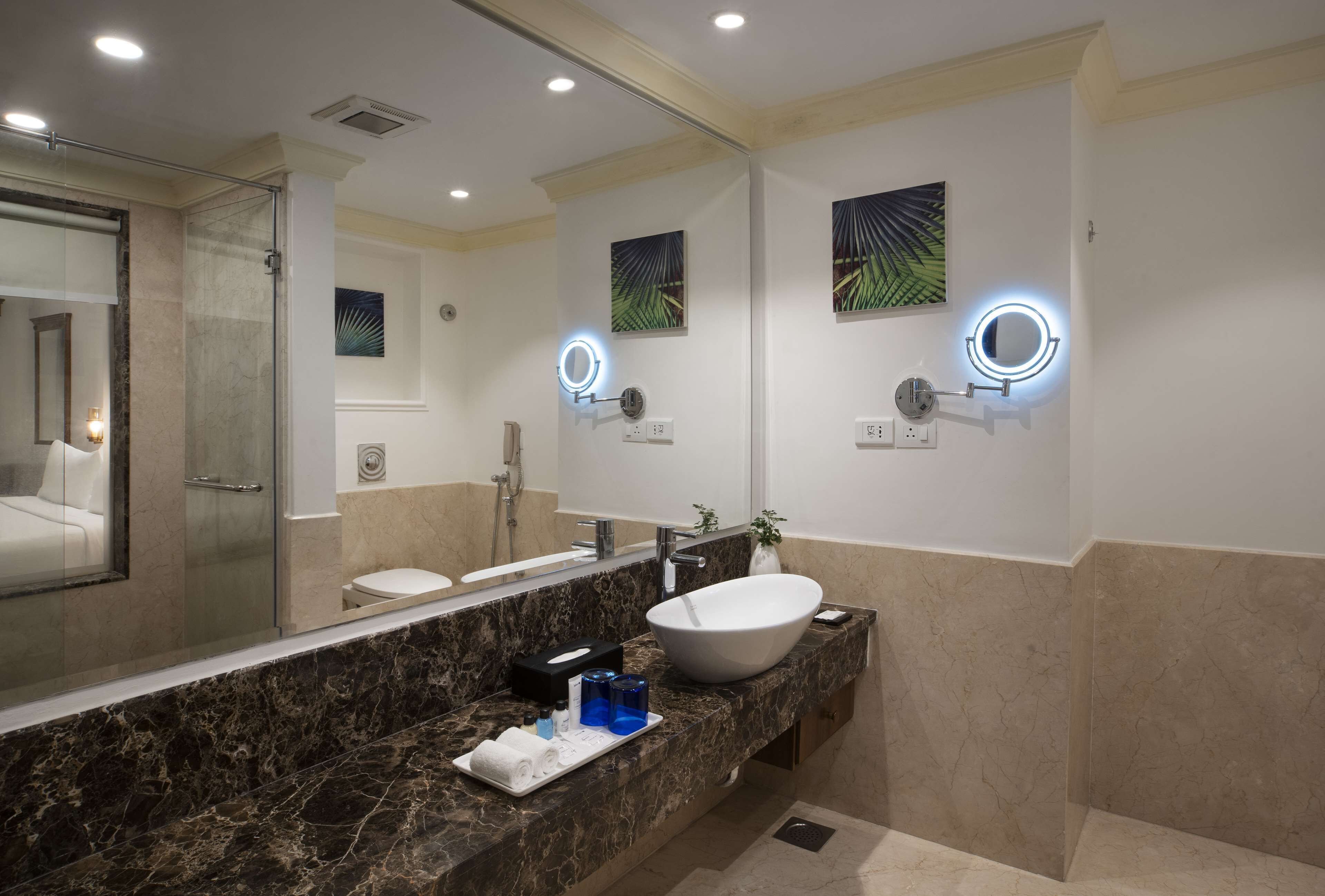 Un baño moderno con un espejo grande, un lavabo blanco y una cabina de ducha de vidrio.