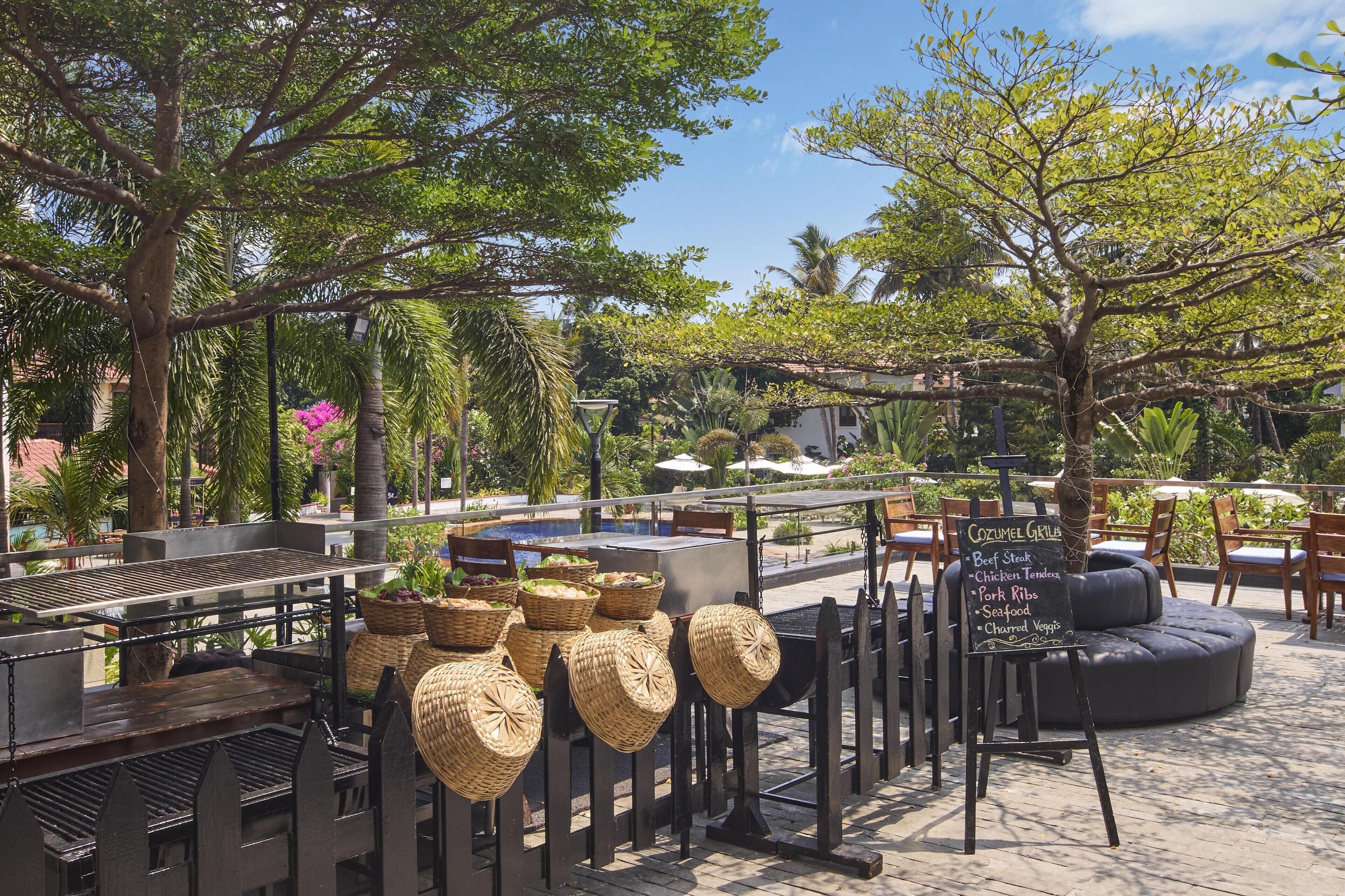 An outdoor dining area with a grill station, wicker baskets, and a menu board.