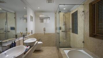 A bathroom with a large bathtub, a double sink vanity, a glass-enclosed shower, and a large mirror.