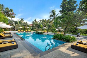 A swimming pool with lounge chairs and umbrellas, surrounded by tropical plants. - Radisson Blu Resort Goa Cavelossim Beach (Cavelossim)