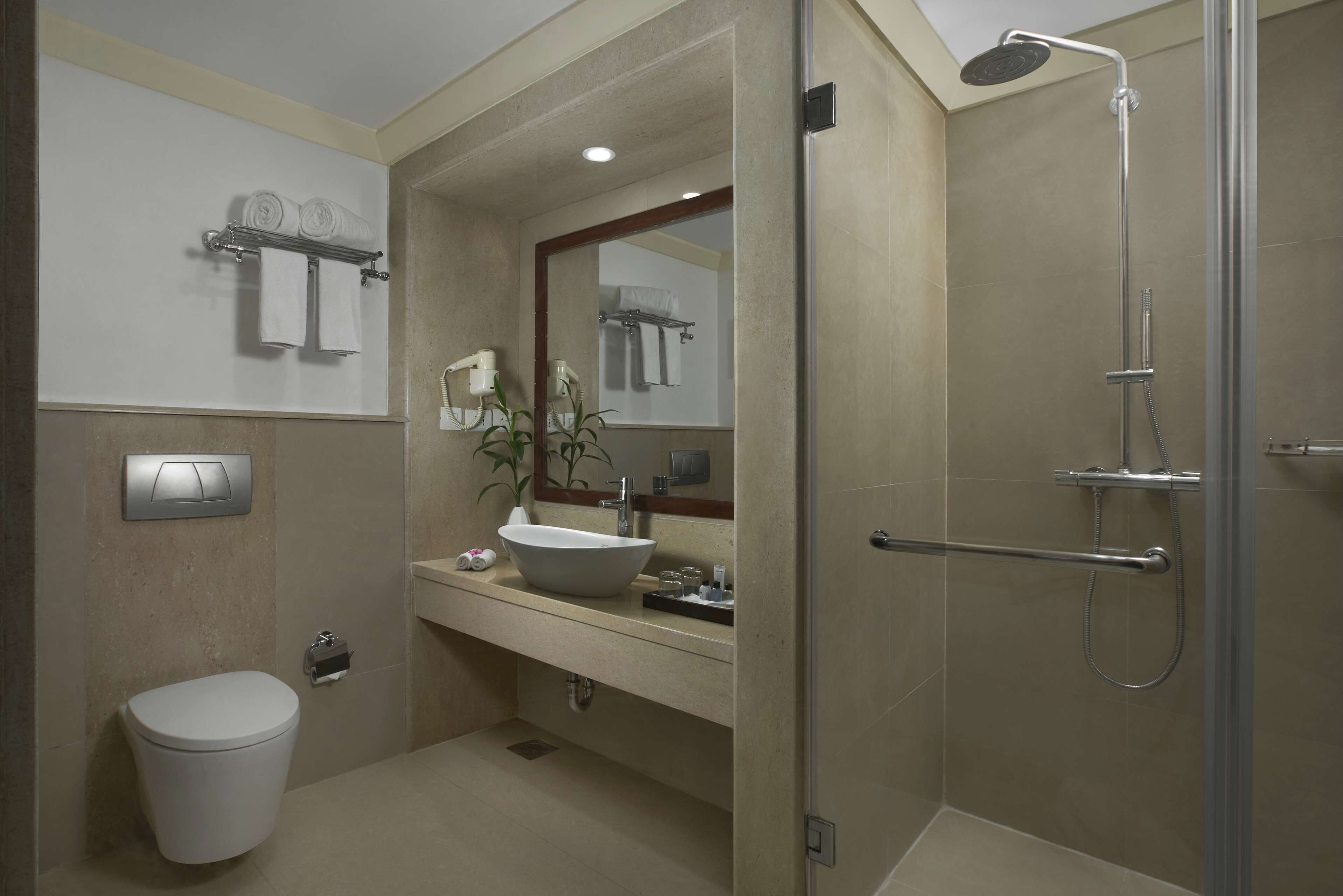 Een moderne badkamer met toilet, wastafel, douche en spiegel.