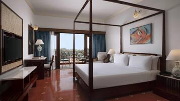 A four-poster bed with a balcony, a television, a desk, and a chair.