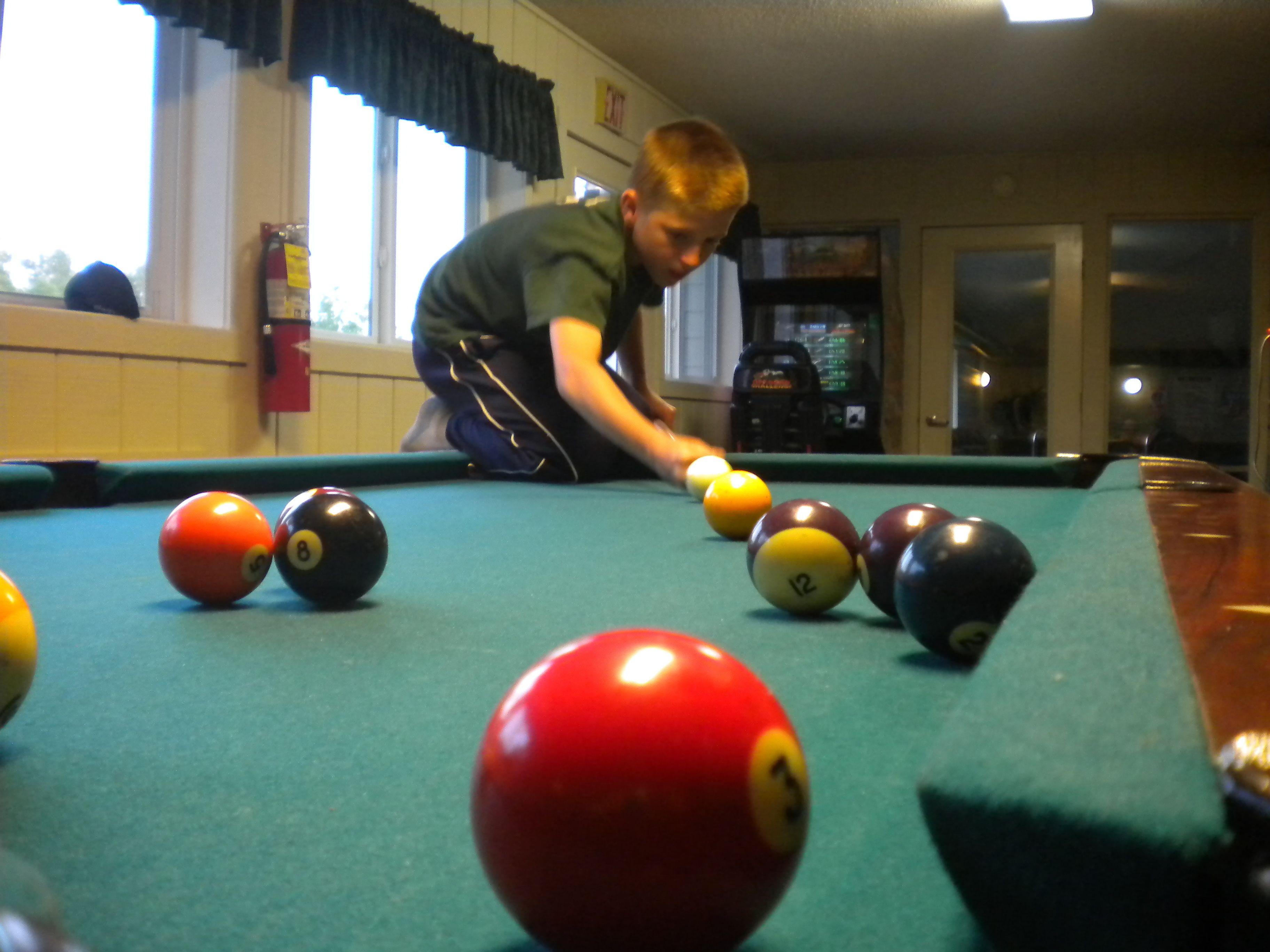 A pool table with balls and a person playing.