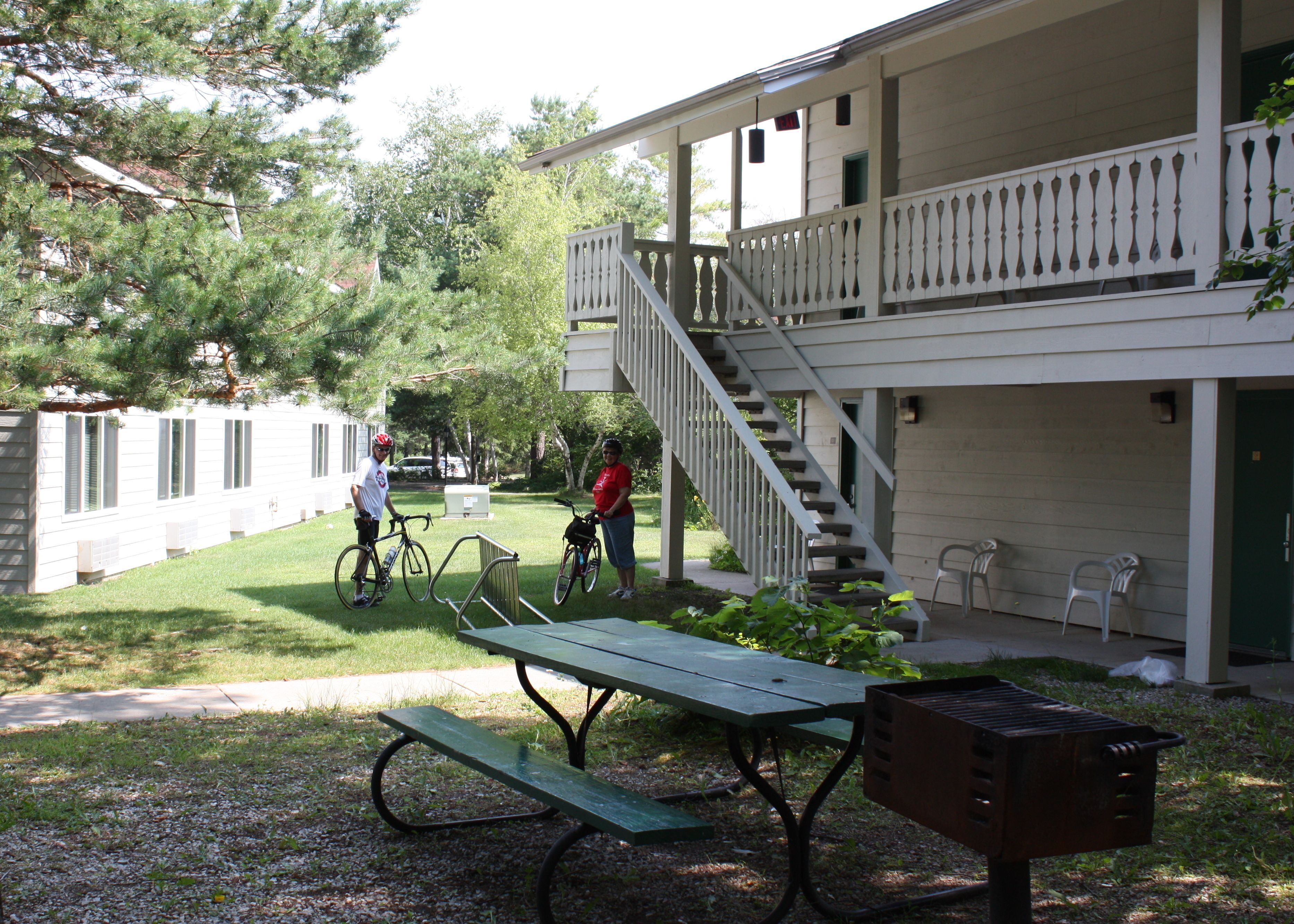 A building with a covered porch, a staircase, and a picnic table.