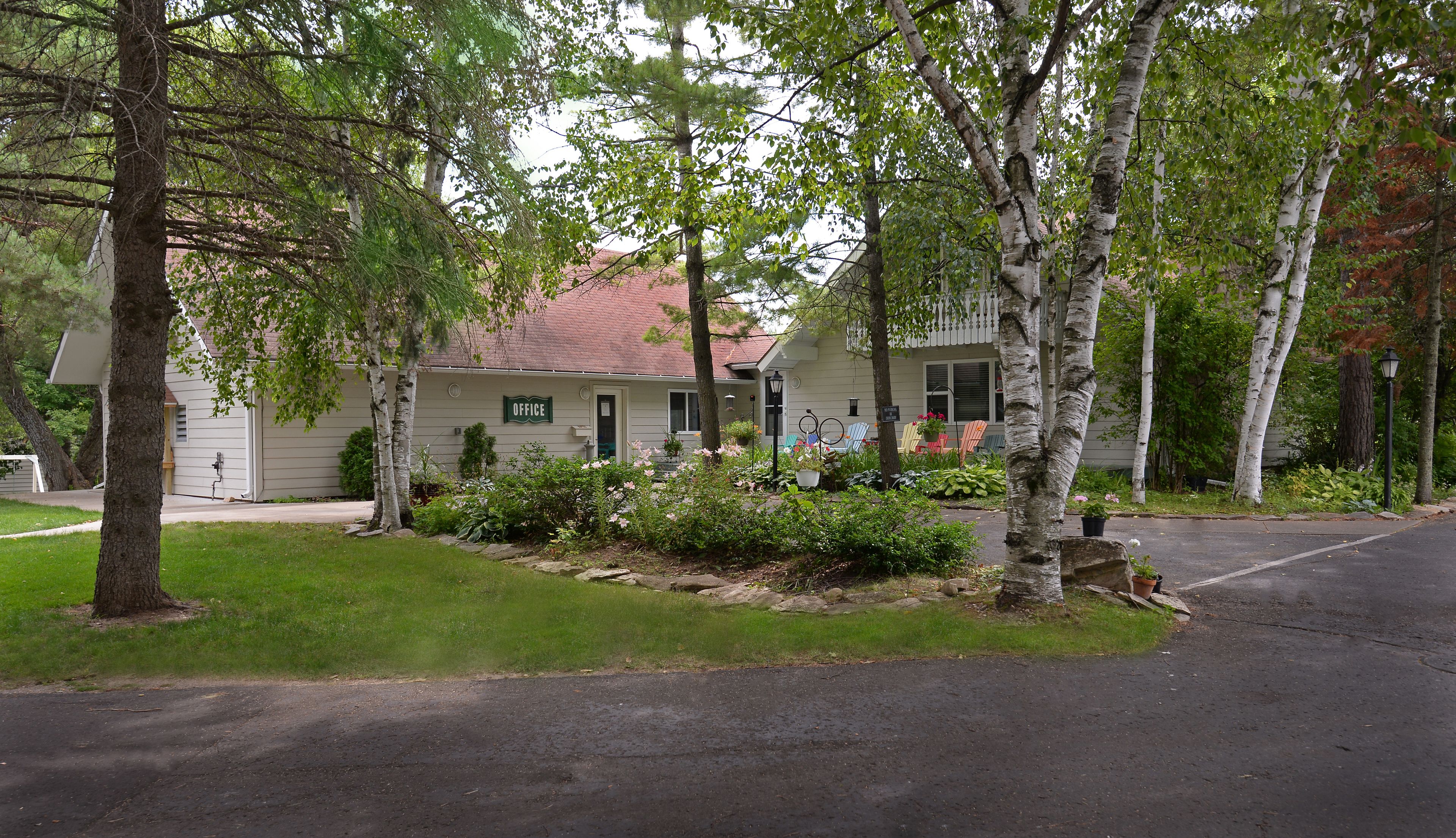 A residential house with a front porch, a mailbox, and a garden with various plants and flowers.