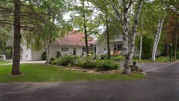A residential house with a front porch, a mailbox, and a garden with various plants and flowers.