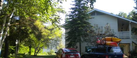 A two-story house with a garage, parked cars, and kayaks on the roof.