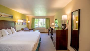 A hotel room with a large bed, a desk, a chair, a dresser, and a mirror.