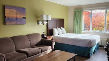 A hotel room with a bed, a sofa, a coffee table, and a painting on the wall.