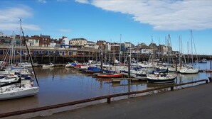 A marina with various boats docked, a waterfront promenade, and buildings in the background. - The Tennyson (Bridlington)