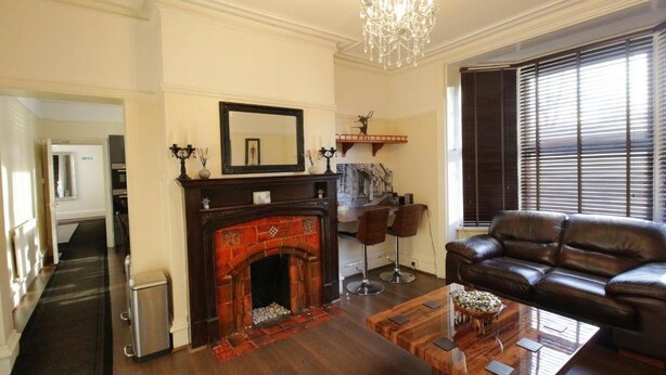 Una sala de estar con chimenea, sofá de cuero y candelabro.