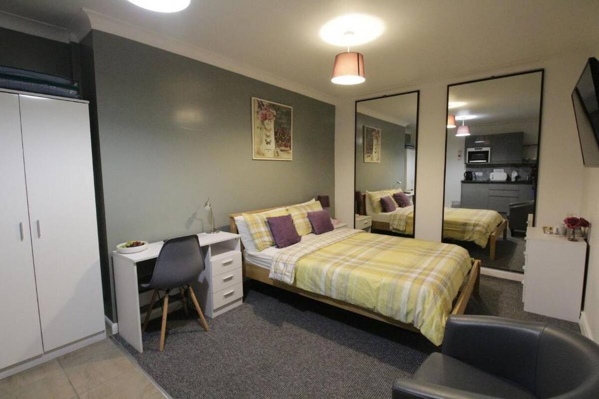 Quarto com cama, escrivaninha, cadeira, guarda-roupa e espelho.
