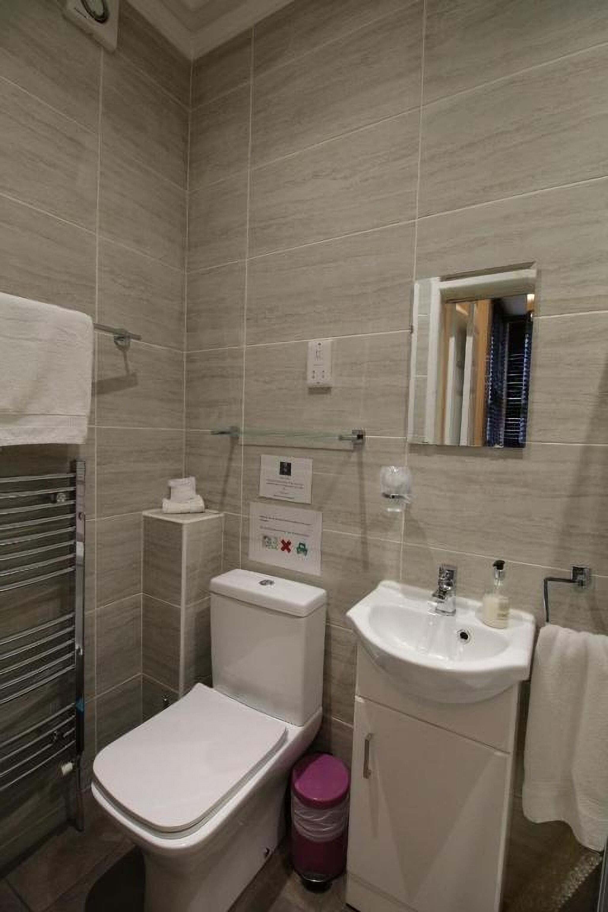 A modern bathroom with a toilet, sink, and mirror.