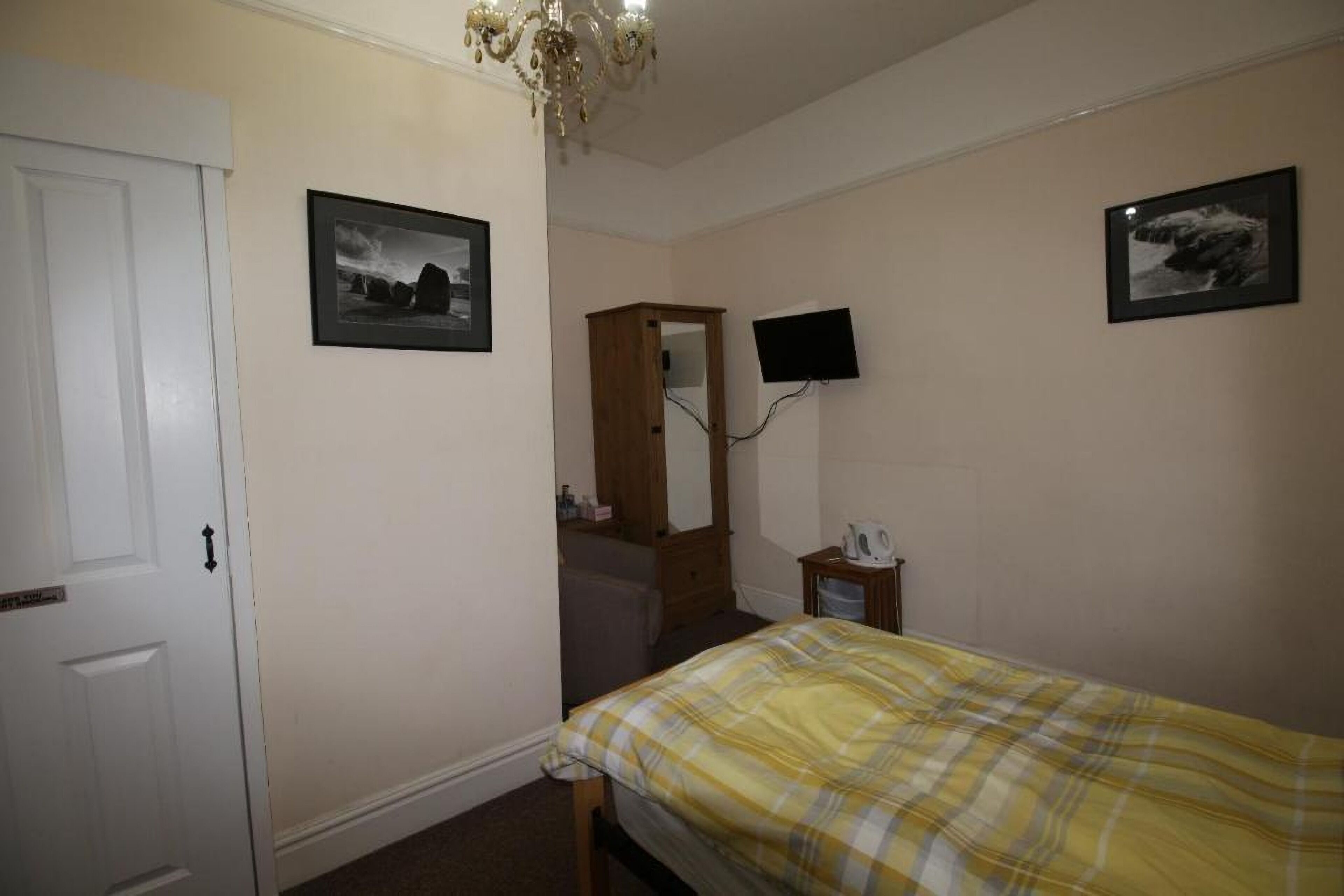 Een slaapkamer met een bed, een dressoir, een spiegel en twee televisies aan de muur.