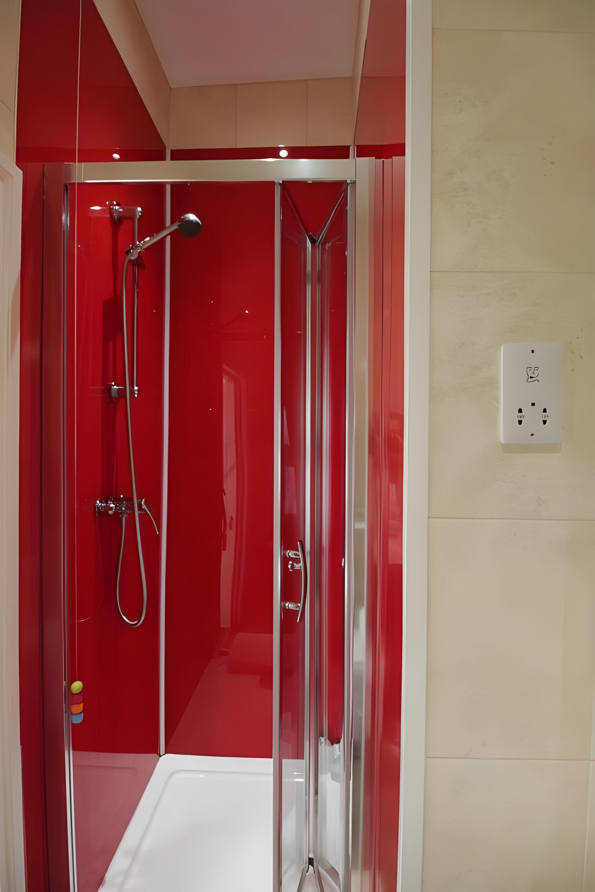 A glass-enclosed shower stall with chrome fixtures and a red interior.