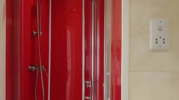 A glass-enclosed shower stall with chrome fixtures and a red interior.