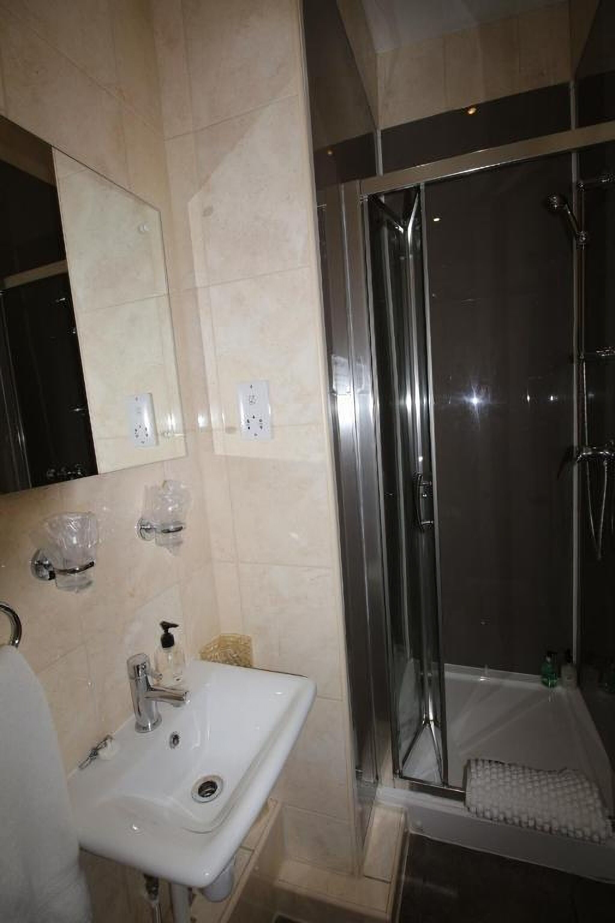 A bathroom with a sink, mirror, and a glass-enclosed shower.