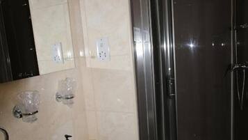 A bathroom with a sink, mirror, and a glass-enclosed shower.