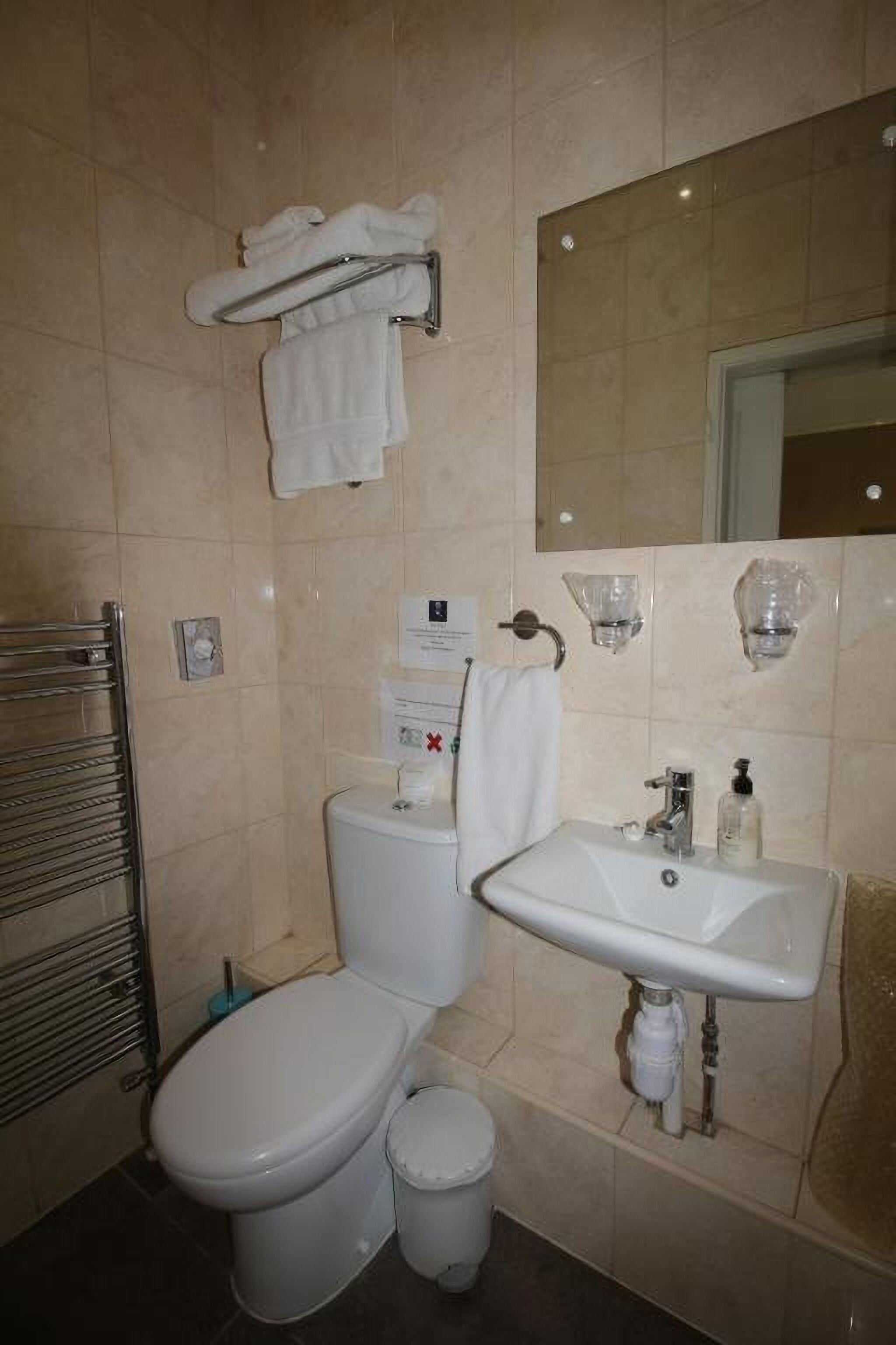 Une salle de bain équipée de toilettes, d’un lavabo et d’un porte-serviettes.