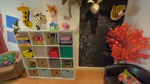 A children's playroom with a bookshelf, stuffed animal decorations, and a chalkboard with writing. - The Sheldon B&B (Eastbourne)