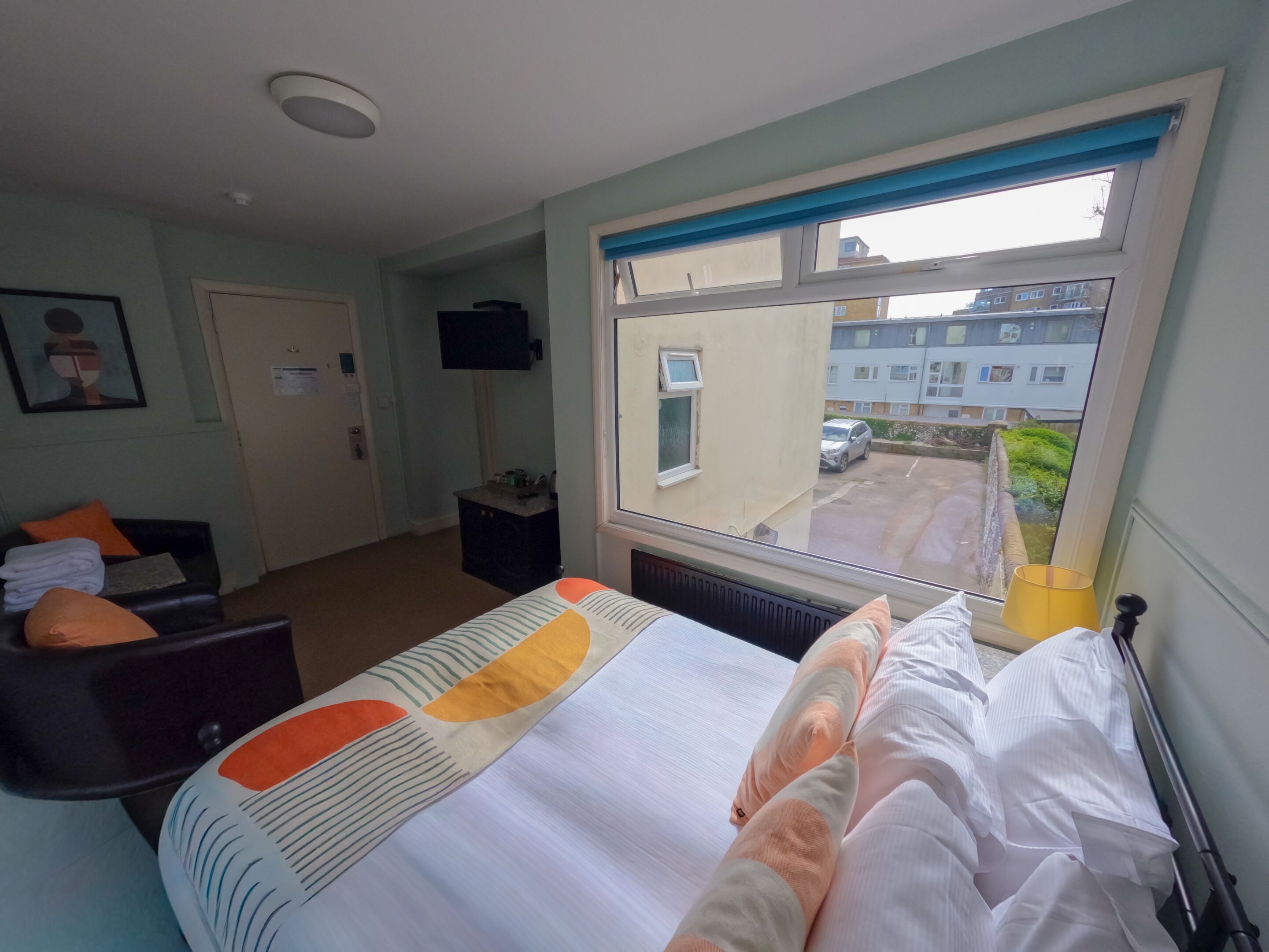 A hotel room with a bed, a desk, a chair, a television, and a window with a view of the outside.
