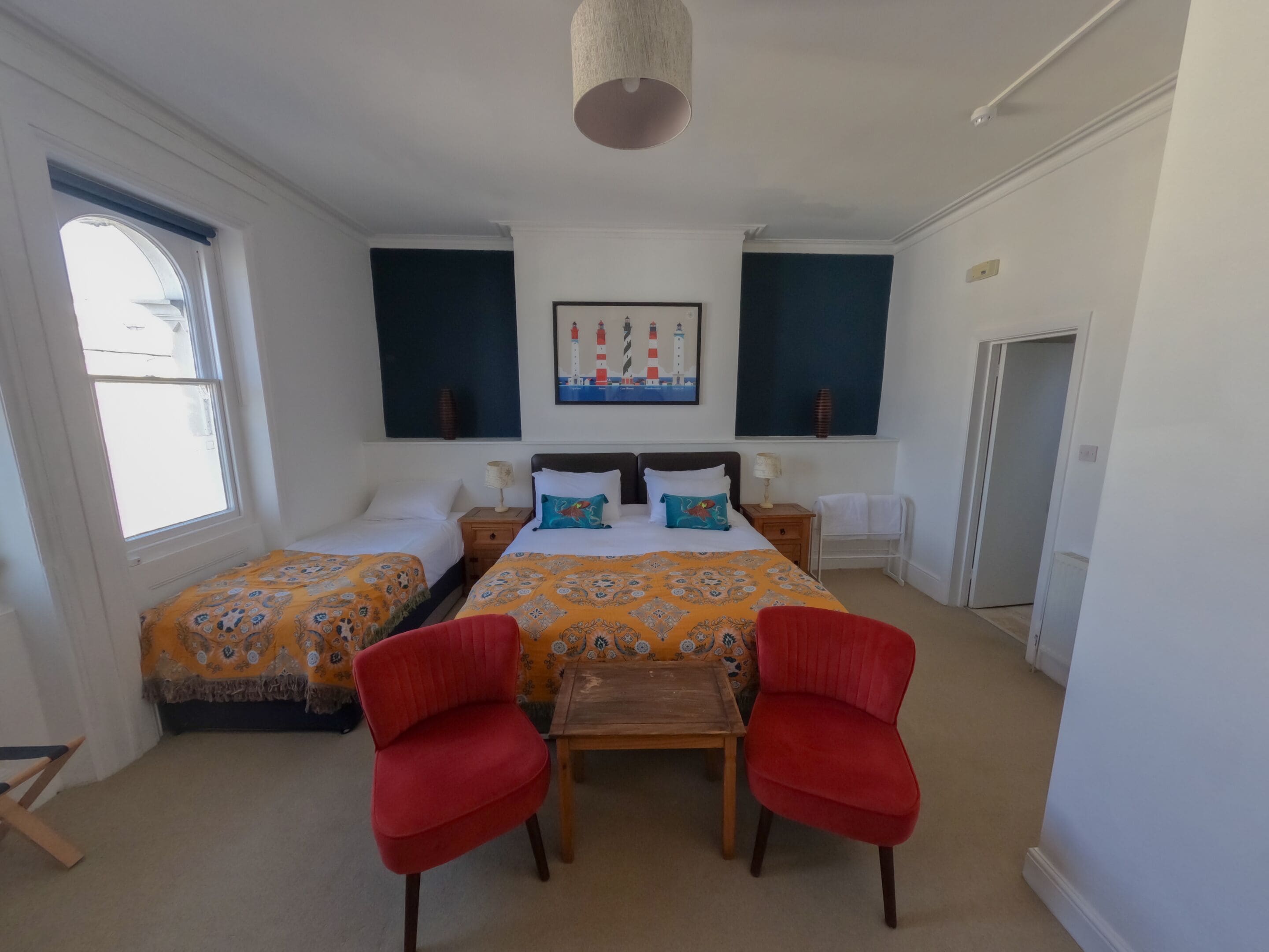 A hotel room with two beds, a dining table, and a red chair.