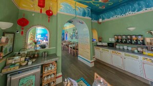 A restaurant with a colorful mural, a coffee station, and a tea station. - The Sheldon B&B (Eastbourne)
