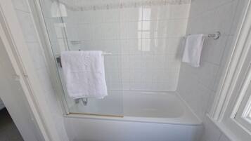 Ein Badezimmer mit einer Duschkabine, einer weißen Badewanne und einem weißen Handtuch an einem Haken.